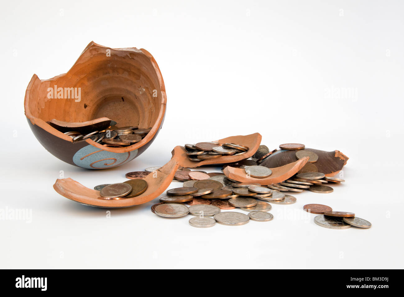 Broken terramundi savings pot with money spilling out over table against a white background Stock Photo