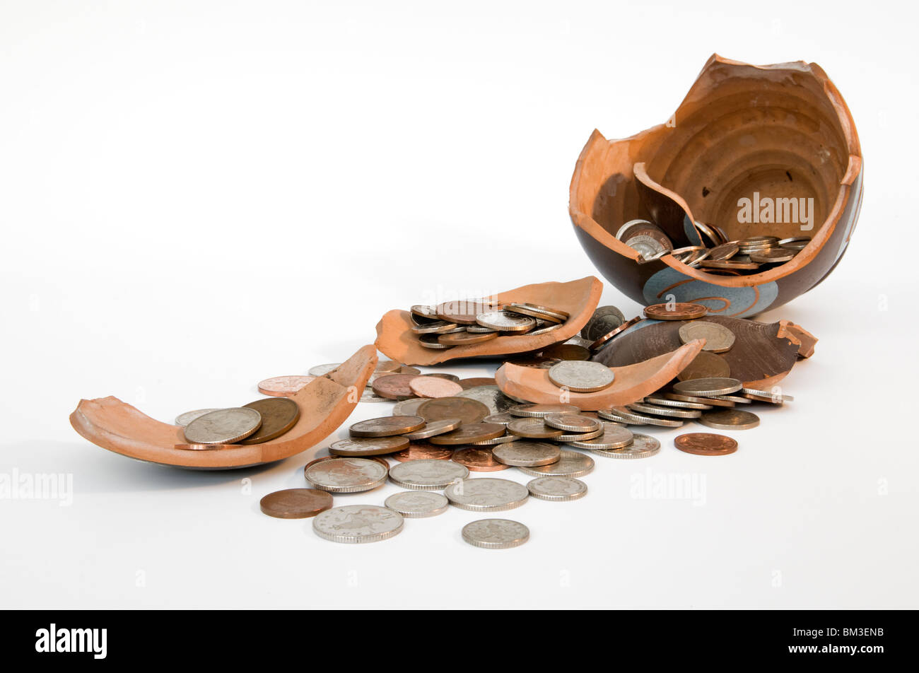Broken terramundi savings pot with money spilling out over table against a white background Stock Photo