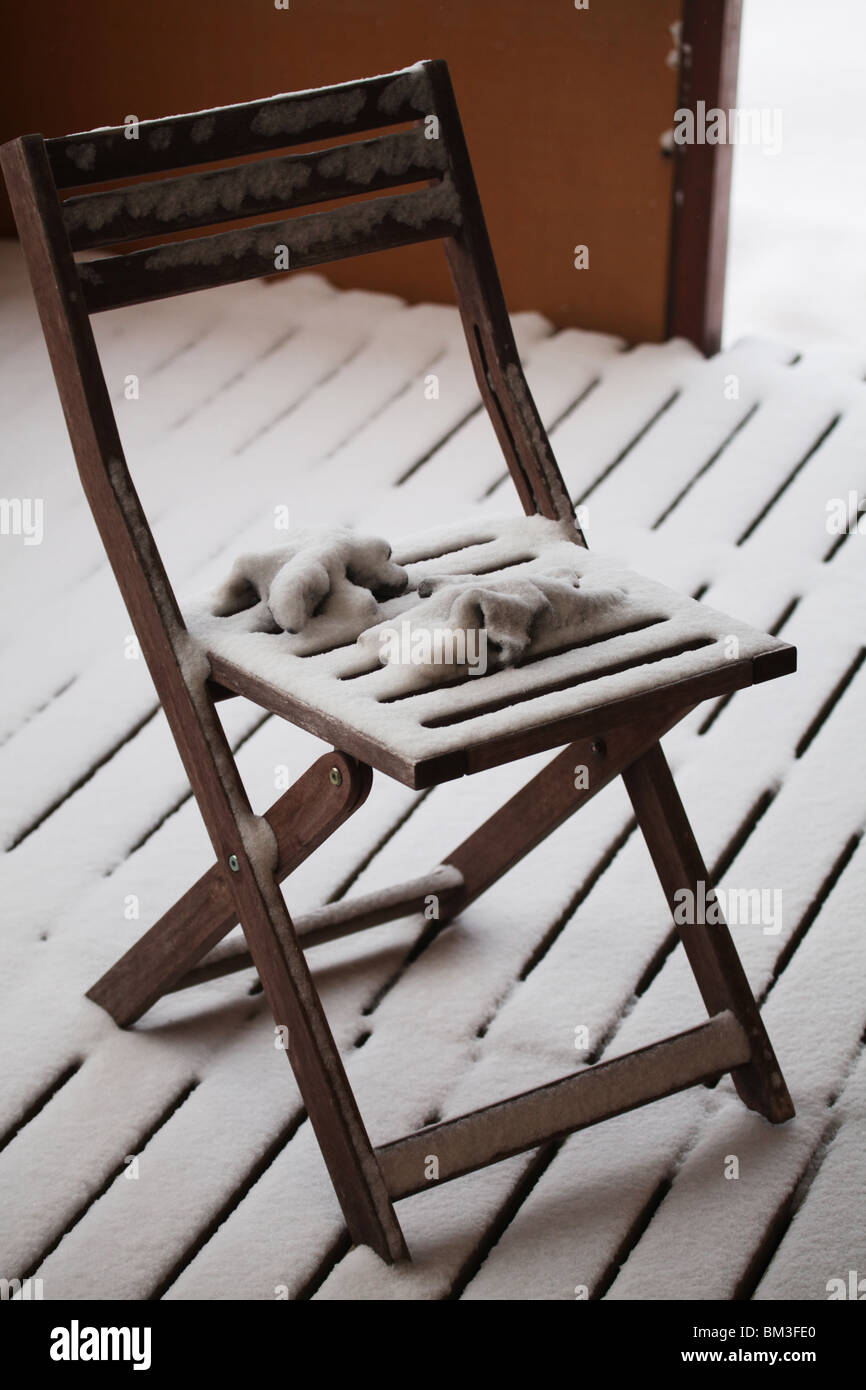 Drifting snow covers garden gloves and folding chair floorboards wooden boards drift drifted Finland Sweden Winter Stock Photo