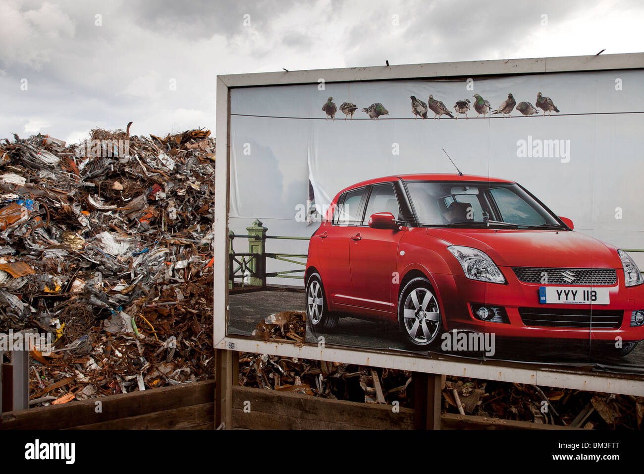 New car billboard in front of a scrap metal heap Stock Photo