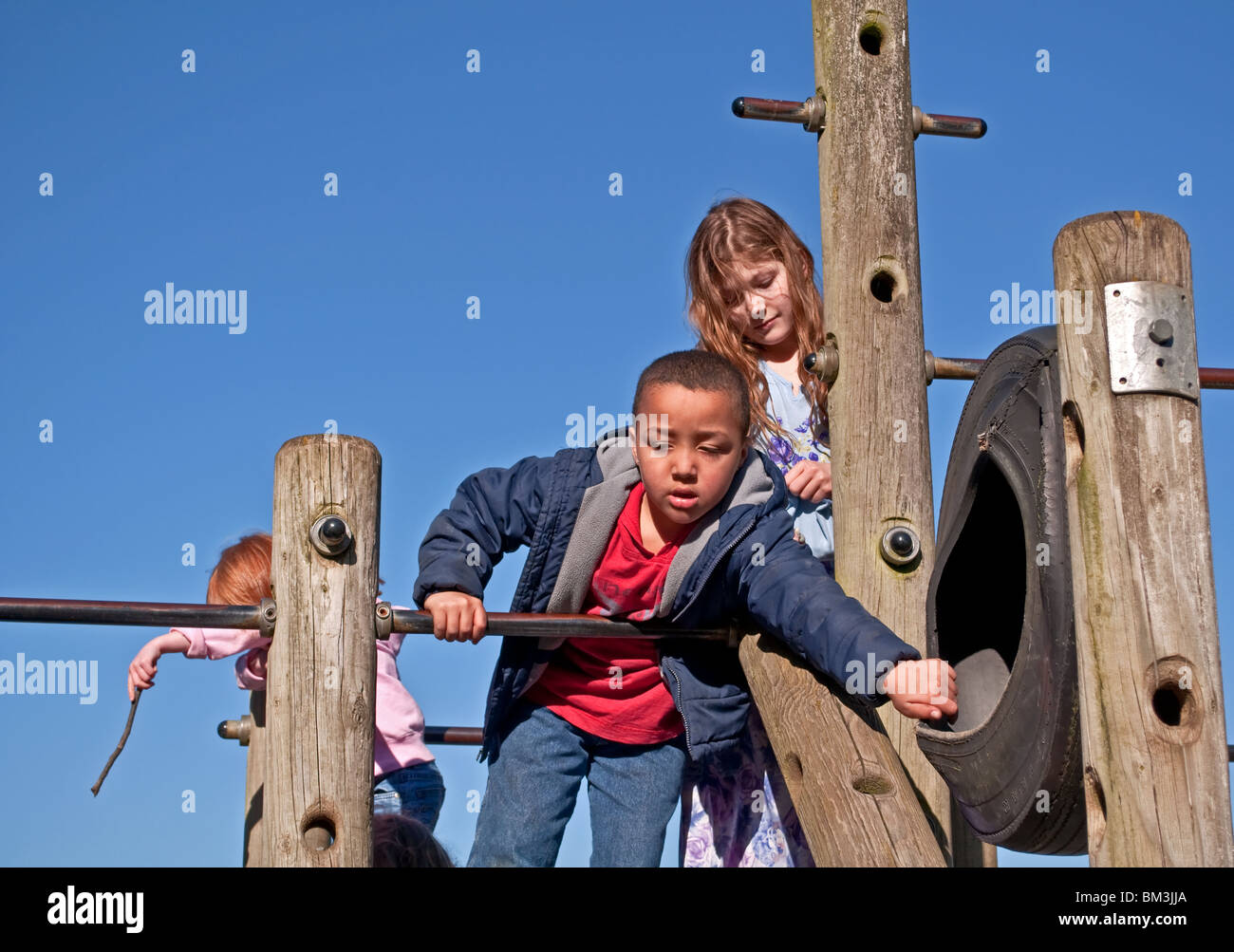 This photo shows diverse children of various cultural races playing outdoors at a park with a bright blue clear sky. Stock Photo