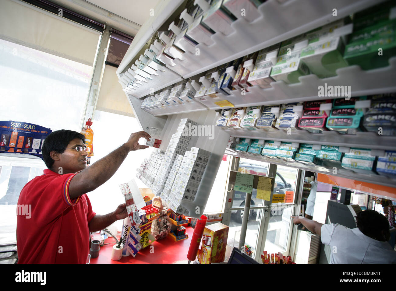 A convenience store clerk at a gas station fills cigarette holders behind the counter. Prices have risen again due to taxes. Stock Photo