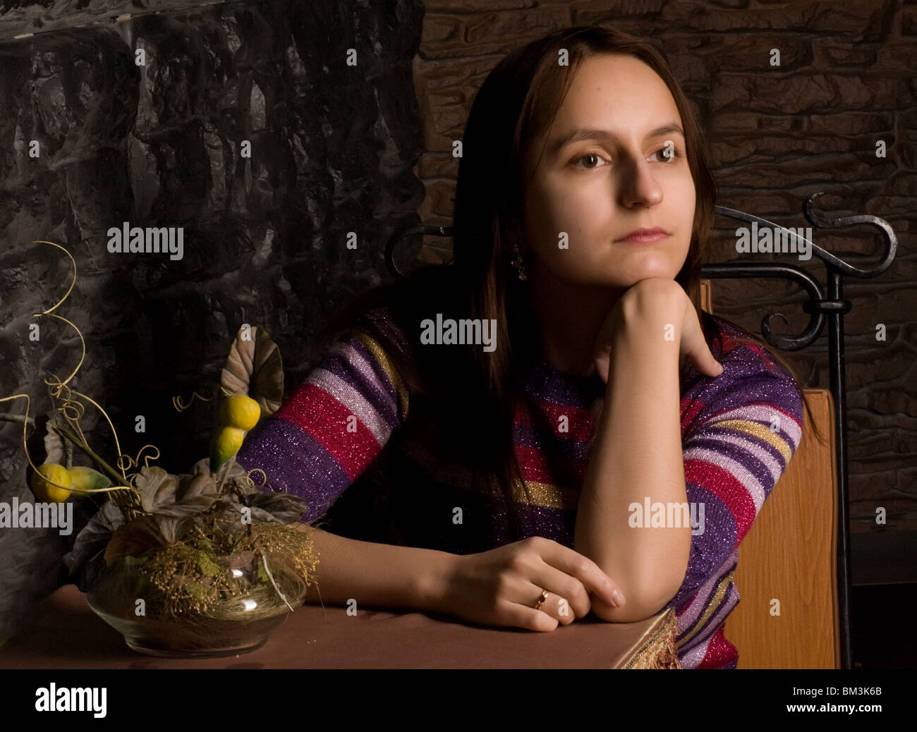 A lonely girl sit at the table in a restaurant and thoughtfully looks aside Stock Photo