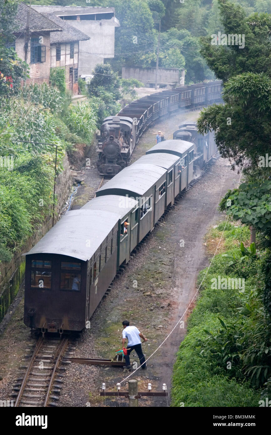 Two steam trains pass a manual switch at a station along the Jiayang steam rail-line in Leshan in Sichuan in China. Stock Photo