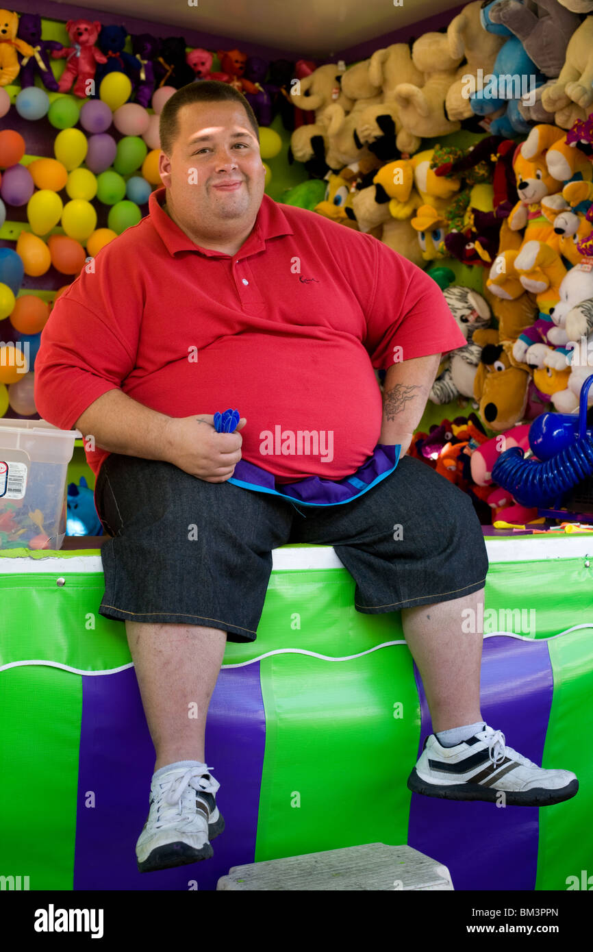Carnival worker aka carny, balloon darts game, New York State, USA Stock Photo