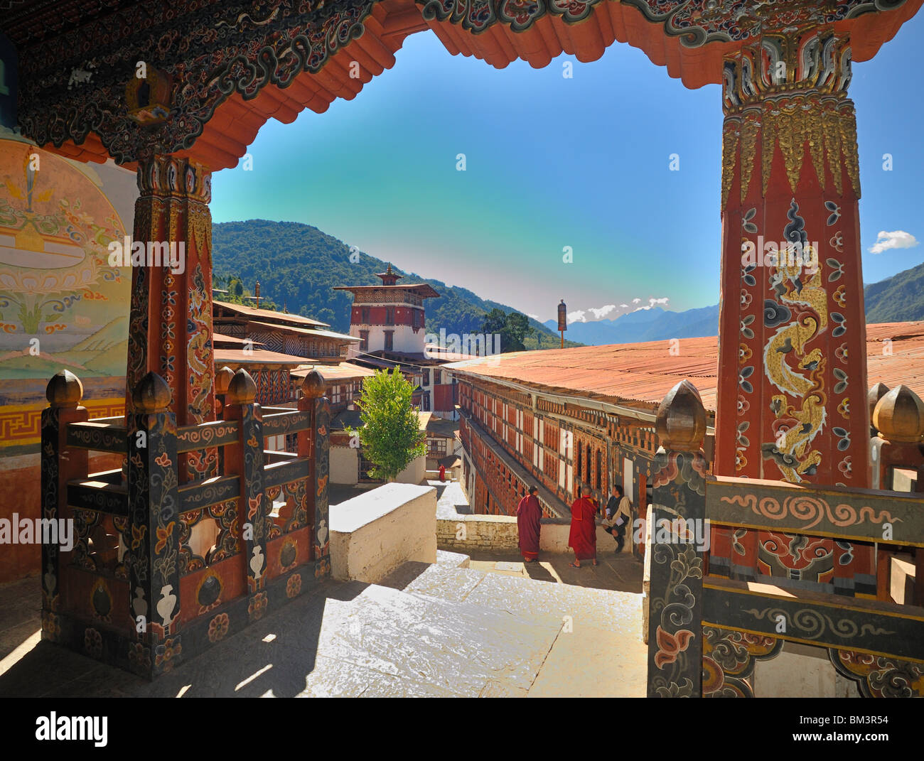 View from temple over courtyard with monks and man in national dress, Trongsa Dzong, Bhutan. Stock Photo