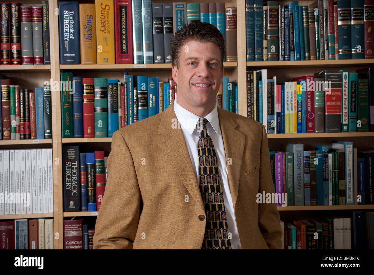 Doctor standing in front of book shelf filled with medical volumes Stock Photo