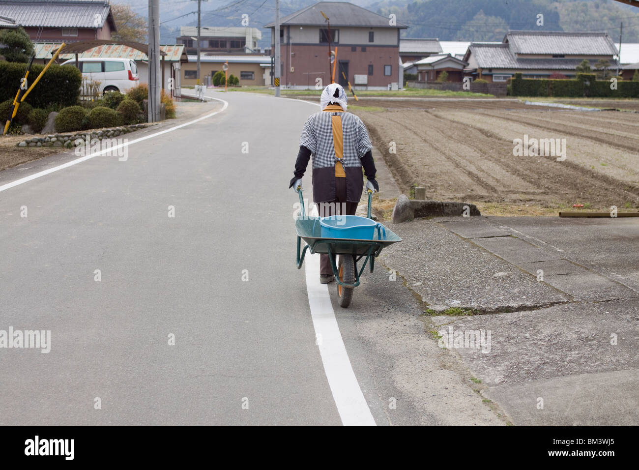 An elderly Japanese woman pulls her wheel barrow around the rural Japanese village of Seiwa, Mie Prefecture part of Taki Town Stock Photo