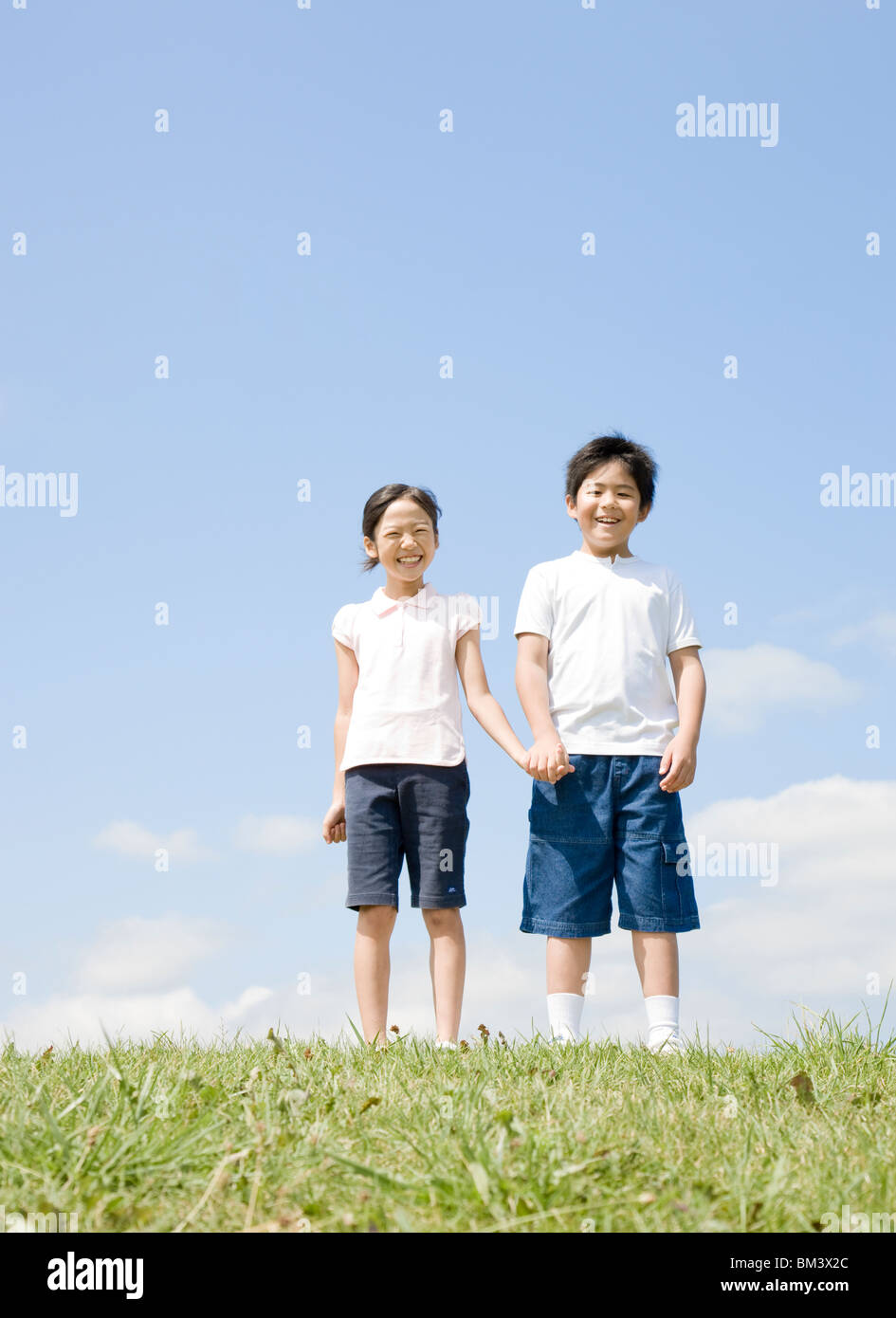 Boy and Girl Holding Hands Under Blue Sky Stock Photo
