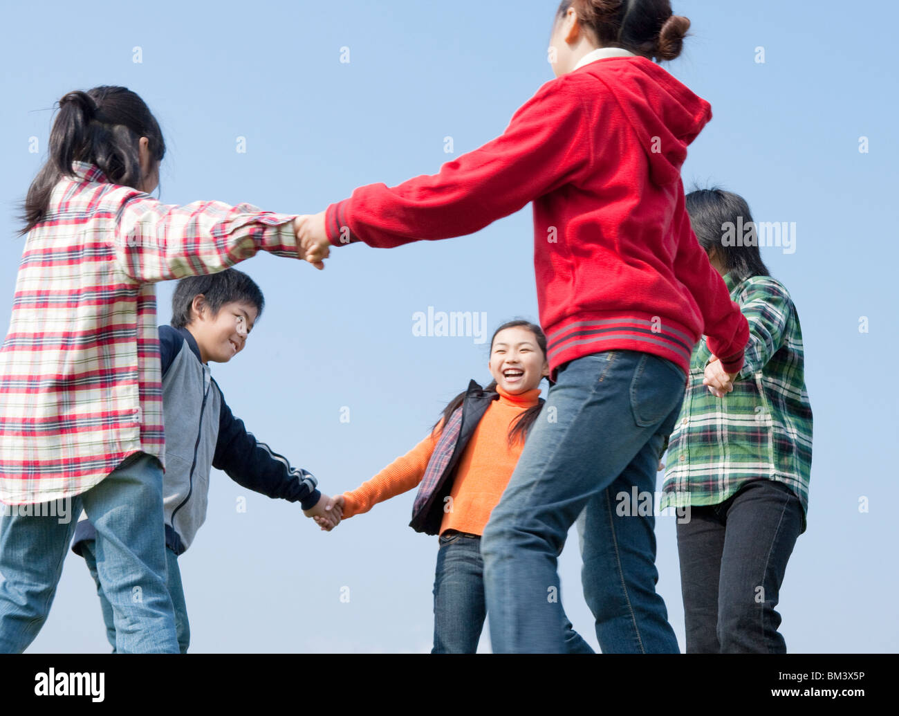 Boys and Girls Holding Hands, Going Around in Circle Stock Photo