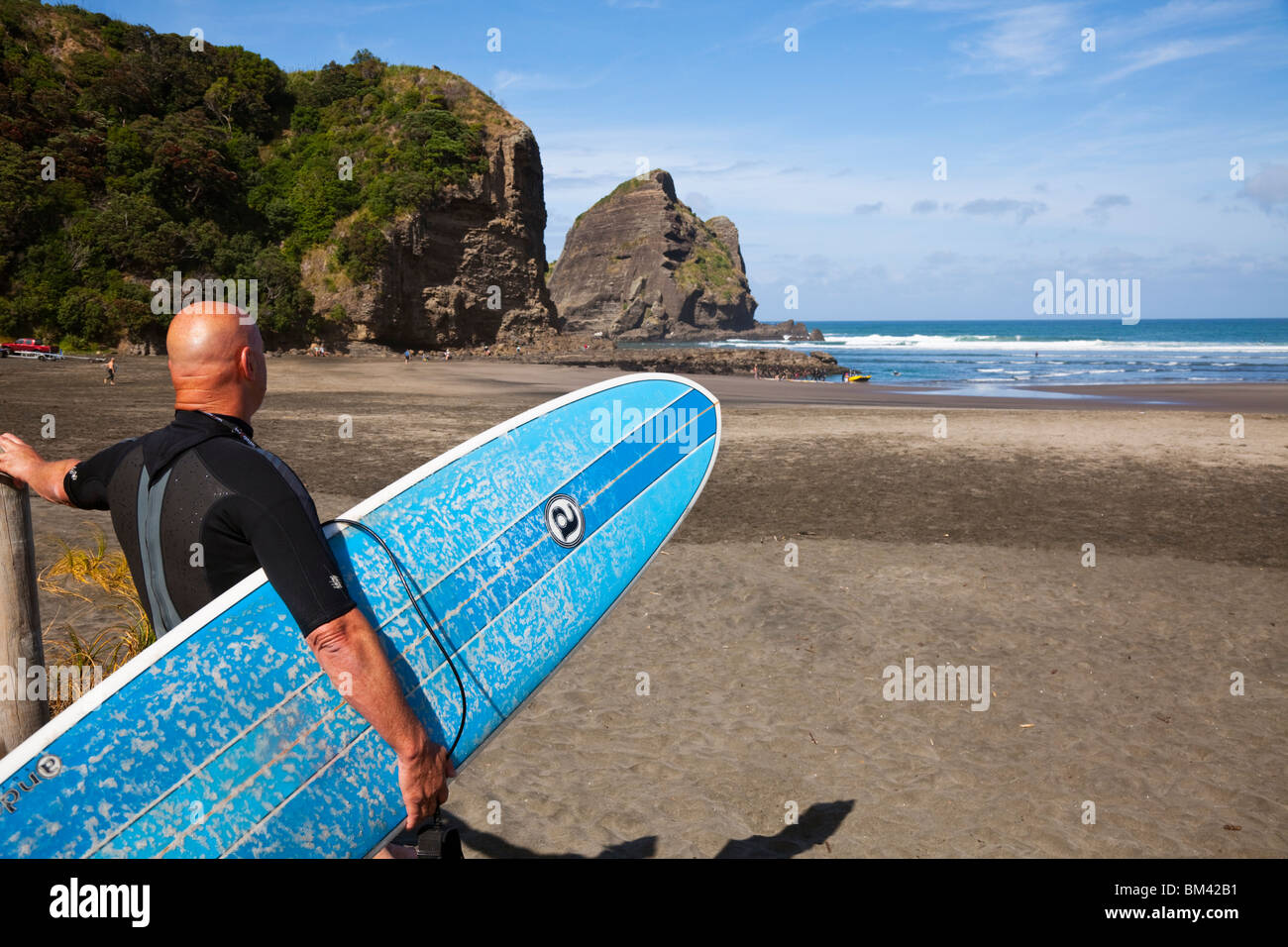 Surfer looking out over Piha beach.  Piha, Waitakere Ranges Regional Park, Auckland, North Island, New Zealand Stock Photo