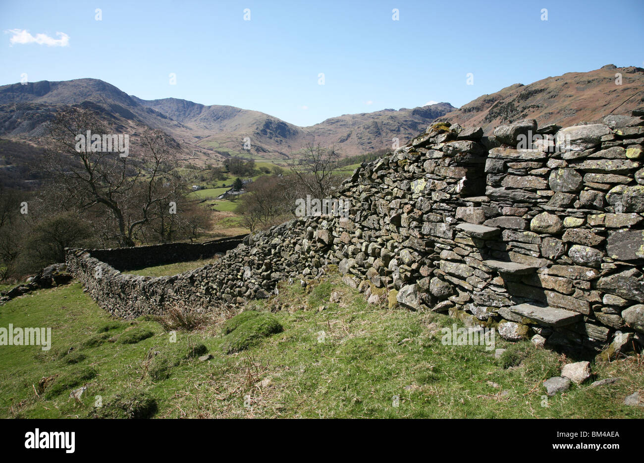 A stile in a dry stone wall looking towards Great Langdale Fells near to Elterwater in the Lake District National Park, Cumbria, Stock Photo