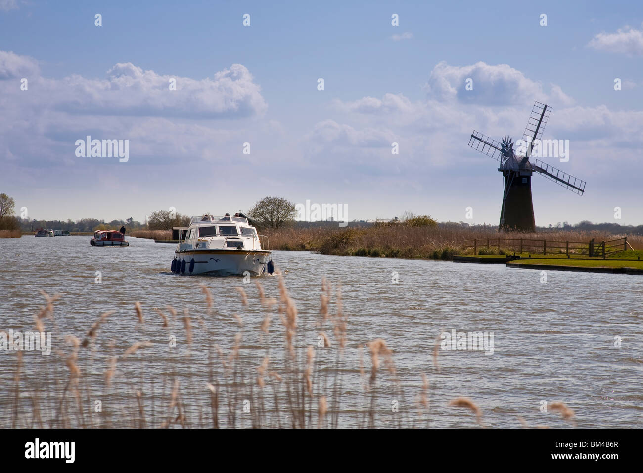 Pleasure boats passing St Benet's mill on the river Thurne at Thurne Norfolk Broads England, UK Stock Photo