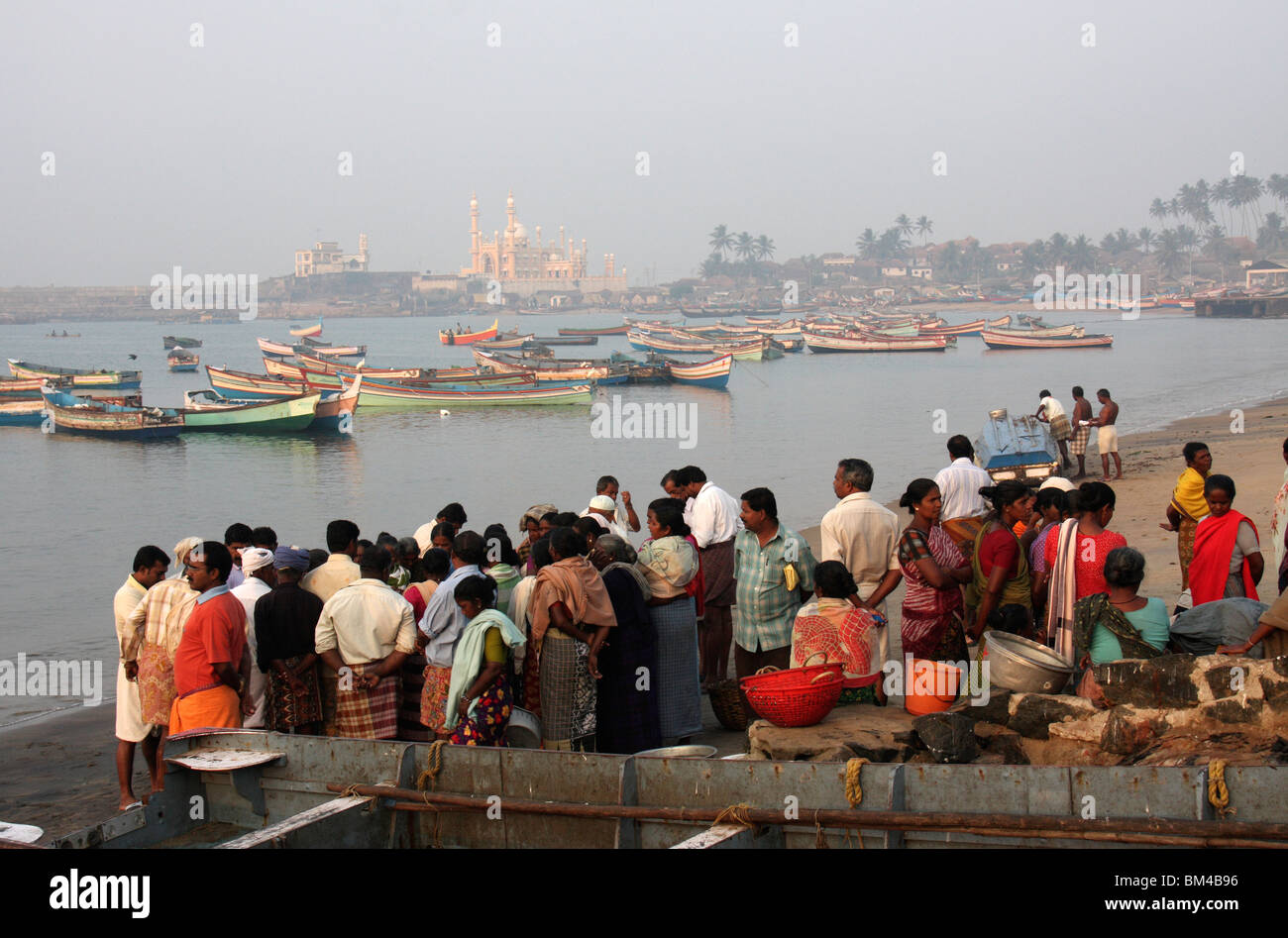 fish sellers and buyers checking fresh catch fish  in the back ground of fishing boats and mosque,vizhinjam beach,kerala,india Stock Photo