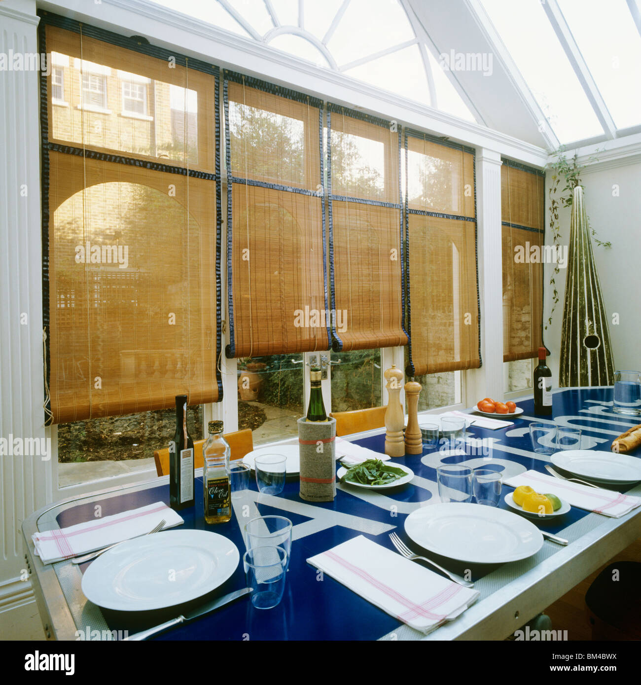 Dining table set in glass roofed conservatory extension in house of designer Rolf Sachs Stock