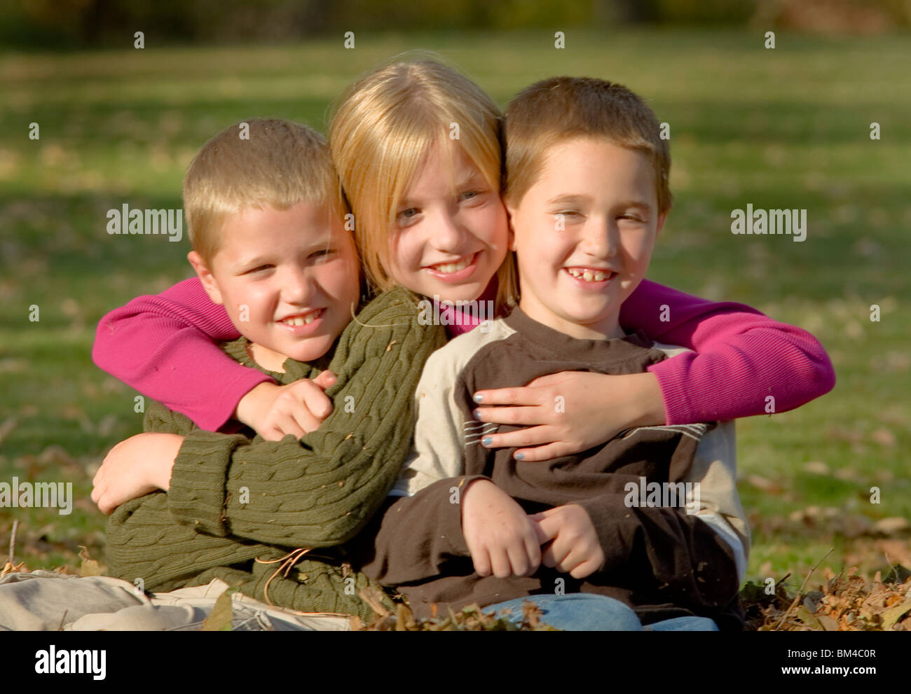 Children sitting in a pile of Autumn leaves Stock Photo