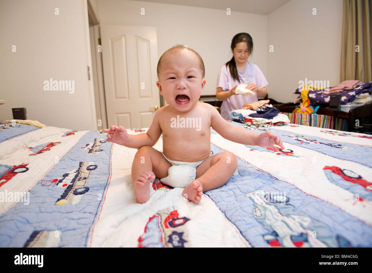 Crying Asian baby boy on bed Stock Photo