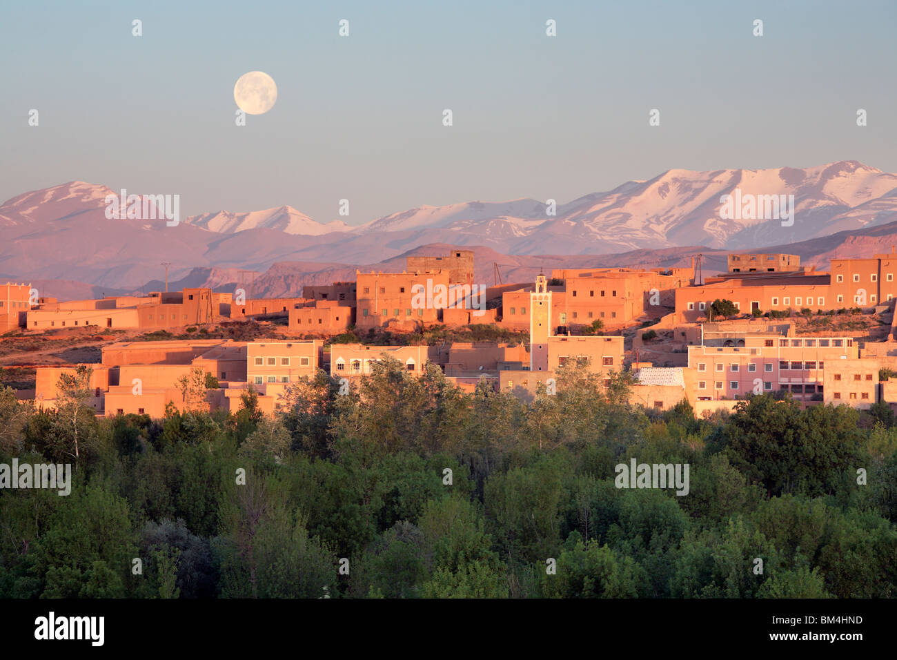 The full moon sets over the Atlas Mountains behind Boumalne du Dades in the Dades Valley of Morocco Stock Photo