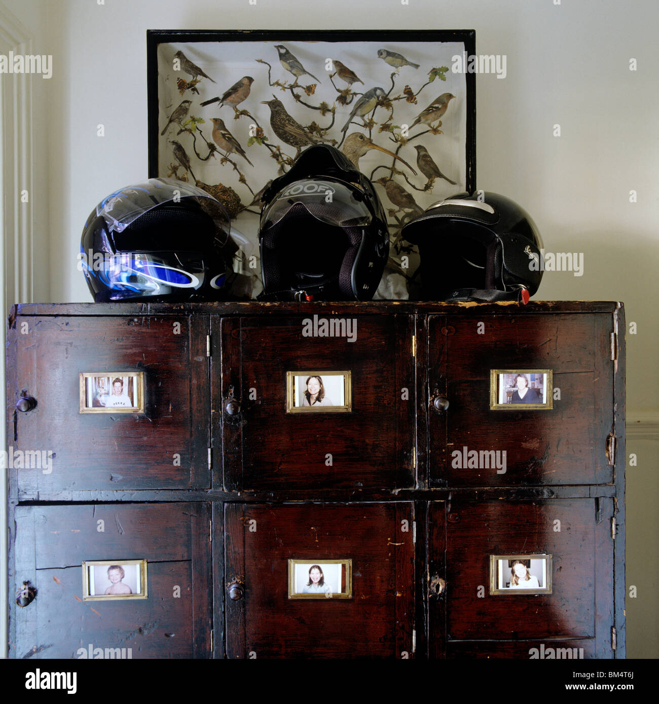 Three motorbike helmets on an old wooden cabinet Stock Photo