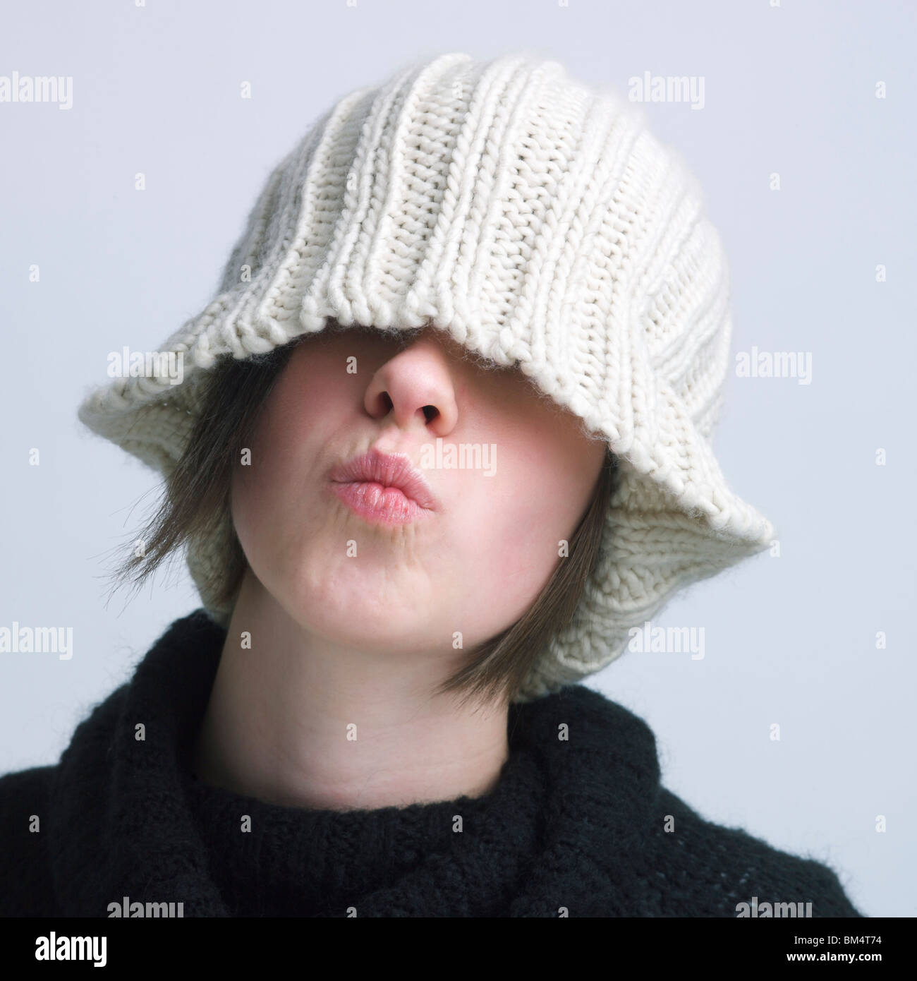 Girl covering eyes with a woolen hat. Stock Photo