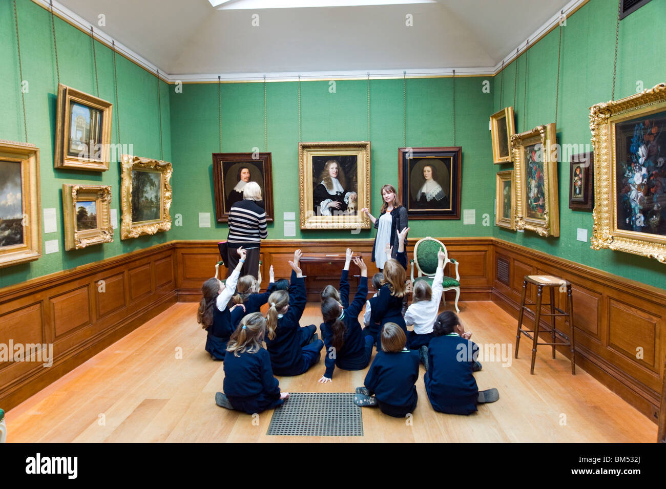 Schoolchildren raising their hands on educational school trip to The Dulwich Picture Gallery, London, UK Stock Photo