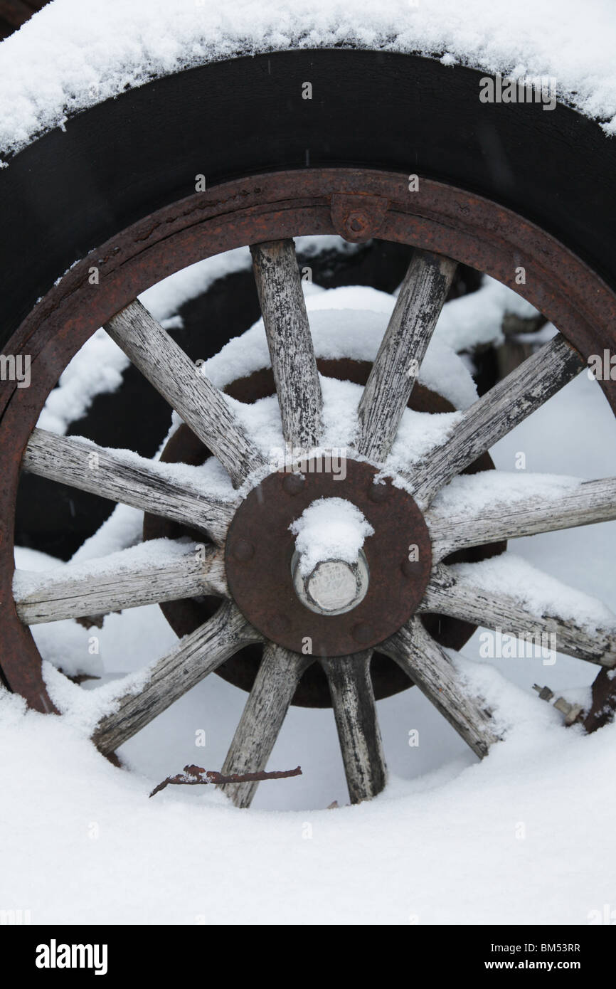 Snow covers an abandoned tractor wooden wagon wheel hub from an ancient vehicle on a farm in Finland Stock Photo