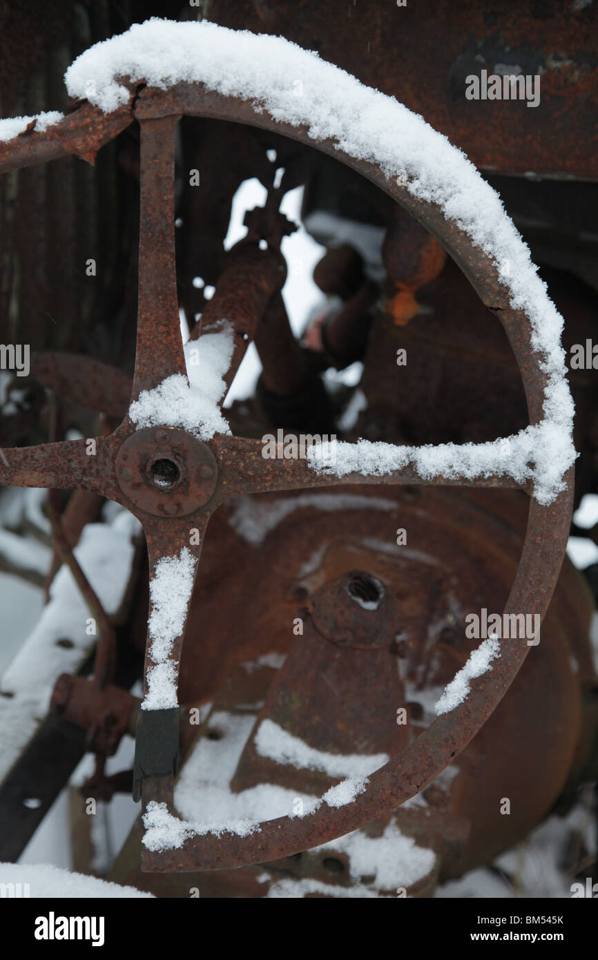 Snow covers a steering wheel on an rusting abandoned antique Ford tractor on a farm in Finland Stock Photo