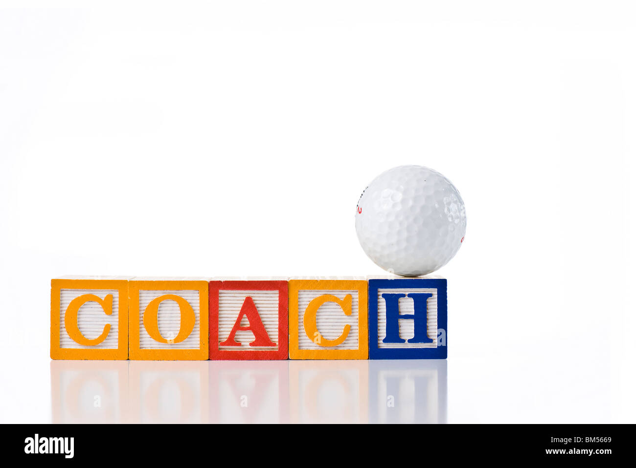 Colorful children's blocks spelling COACH with a golf ball balanced on