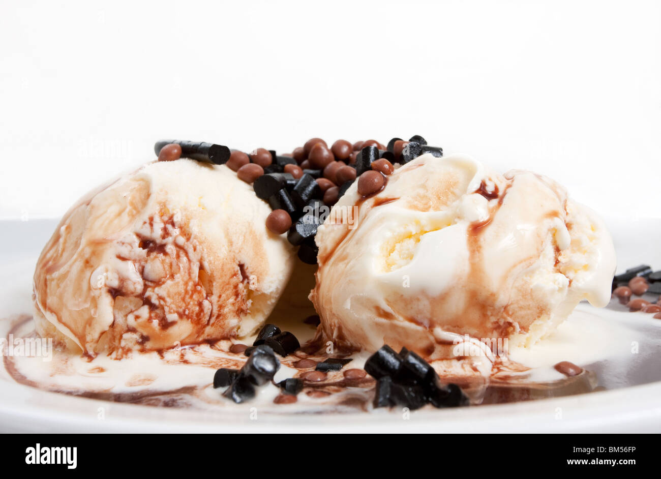 Vanilla icecream on a plate with chocolate sauce and candy topping Stock Photo