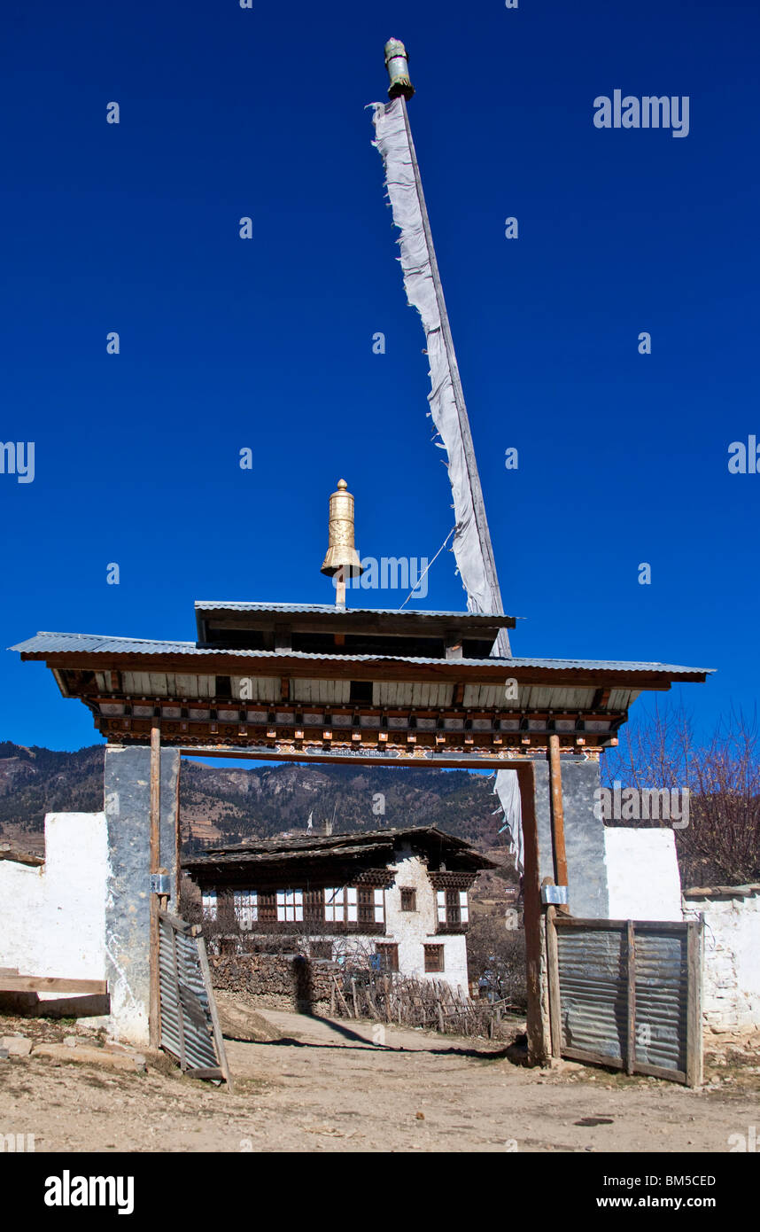 Monastery entrance gate framing village house, Ura, Bumthang, Bhutan Stock Photo