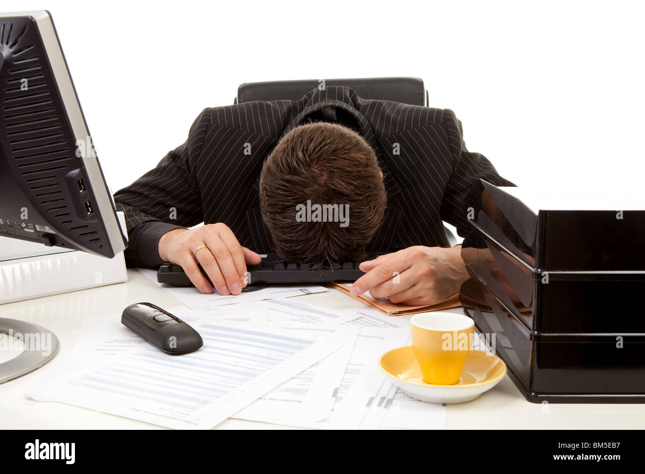 Businessman lies with head on his desk, overwrought and sleeping, over white background Stock Photo