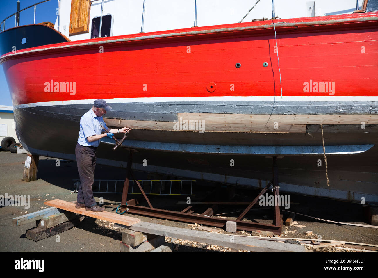 Master ship builder, John Gaff, repairing the hull of a fishing boat using the traditional method of packing oakum into gaps Stock Photo
