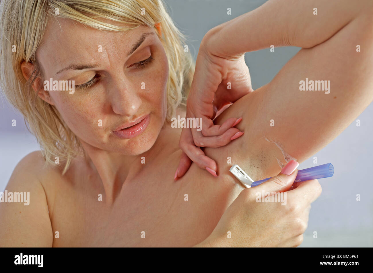 Woman using a disposable razor to shave her armpit Stock Photo
