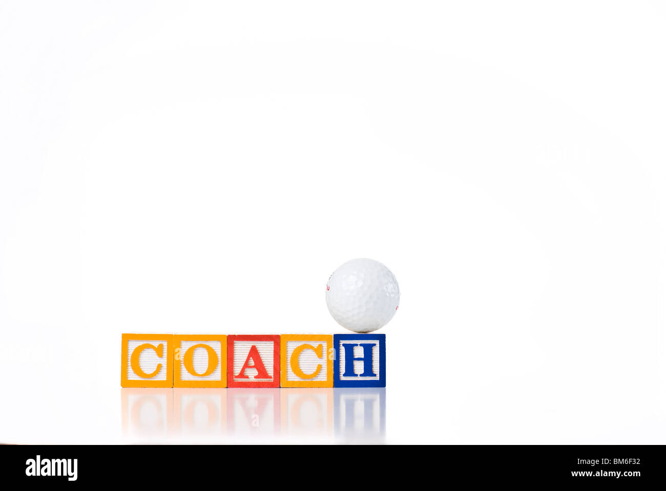 Colorful children's blocks spelling COACH with a golf ball balanced on