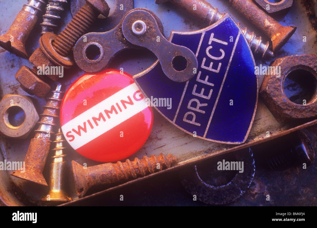 Close up of old metal bits and pieces such as screws and nuts with two badges among them stating Swimming and Prefect Stock Photo