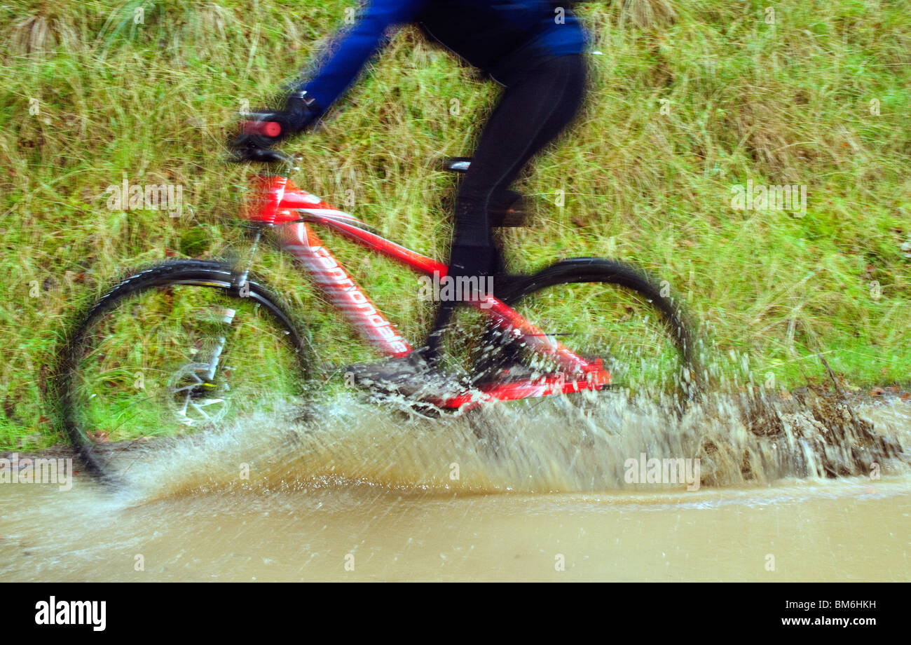 Female mountain biker splashes through a puddle Stock Photo