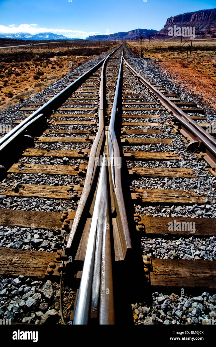 Railroad tracks parallel a highway in Moab, Utah. Note mountains in background. Stock Photo