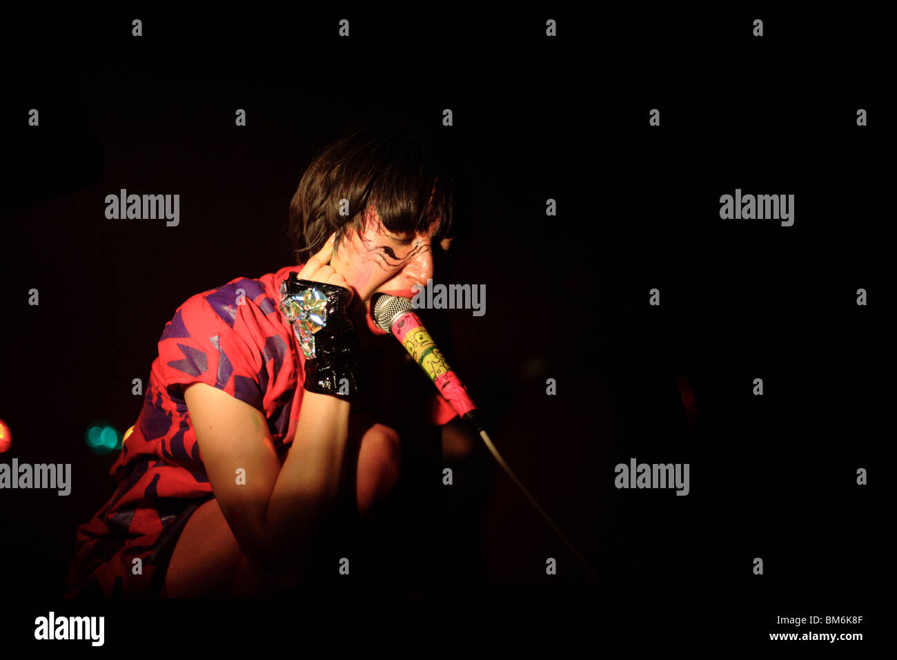 Karen O of the Yeah Yeah Yeahs screaming into a microphone shoved in her mouth at a concert in Omaha, Nebraska. Stock Photo