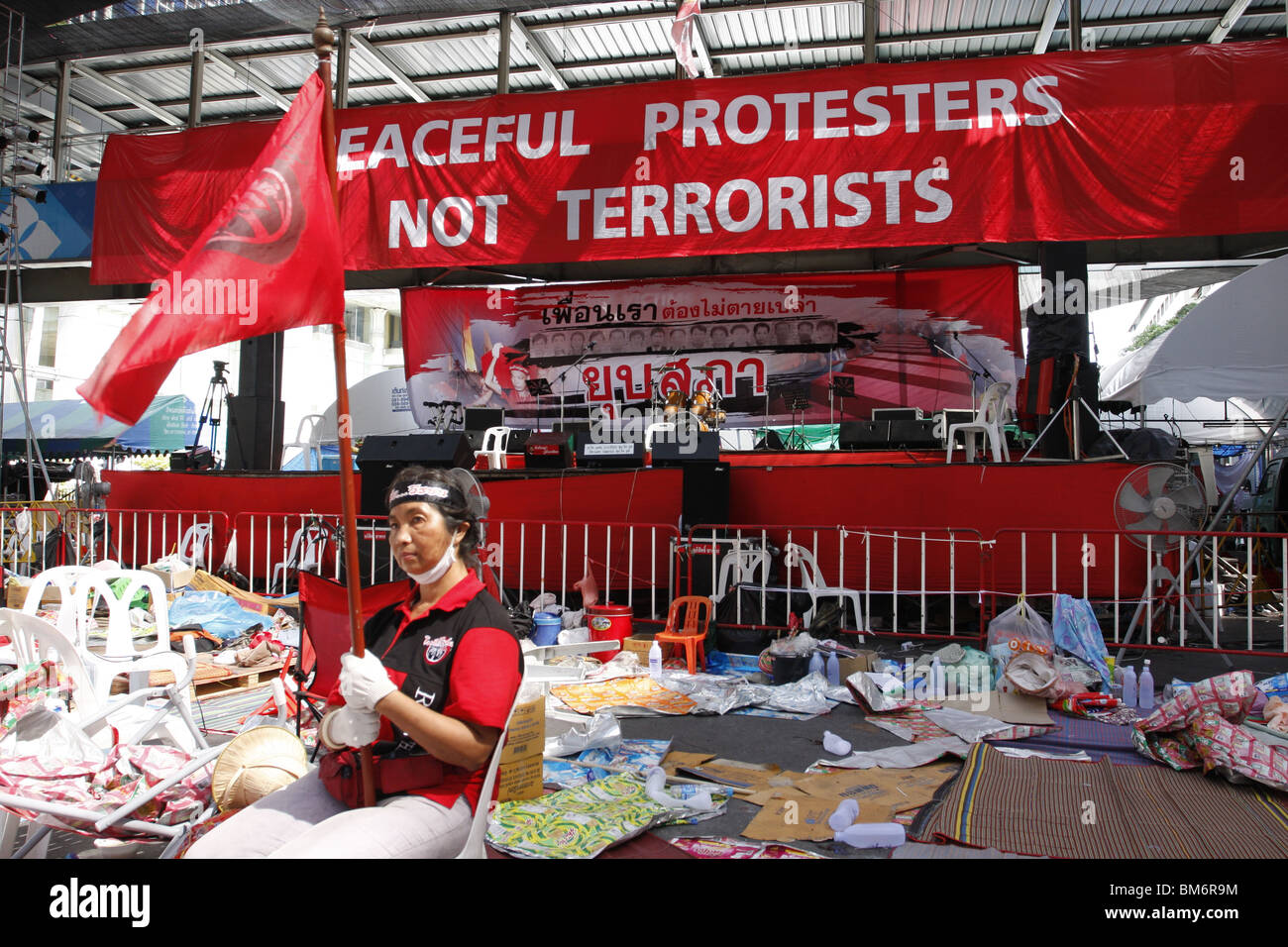 A woman sits defiantly in front of the Red Stage, following the violent end of months long Red Shirt demonstrations in Bangkok Stock Photo
