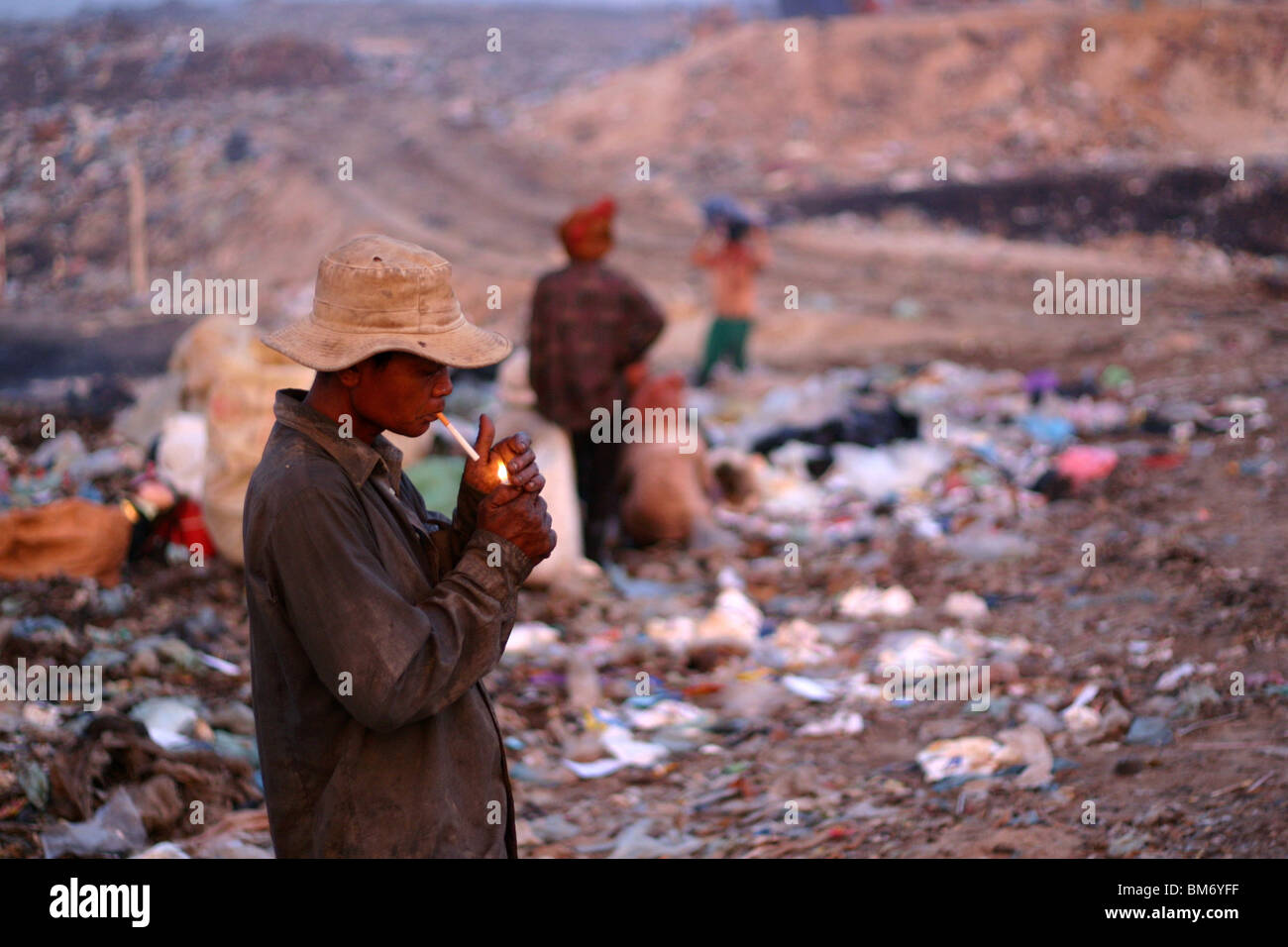 a man ligting a cigarette at the garbage dump in Phnom Penh, Cambodia. Stock Photo