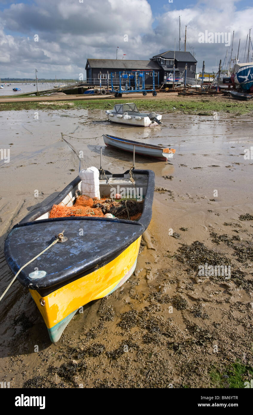 small fishing boat drawn up and beached on the sandy shore at low tide on Mersea Island Essex coast UK Stock Photo