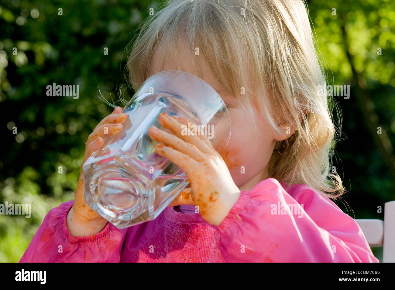 Toddler is drinking water from a glass hires stock photography and