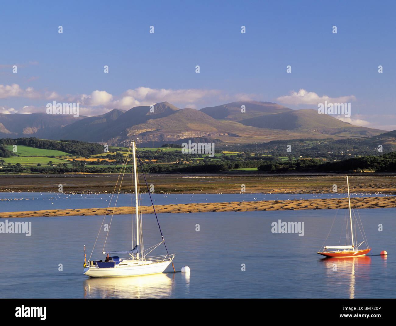 MOORED BOATS on MENAI STRAIT with Lavan Sands and mountains of Snowdonia National Park on mainland seen from Beaumaris Anglesey North Wales UK Stock Photo