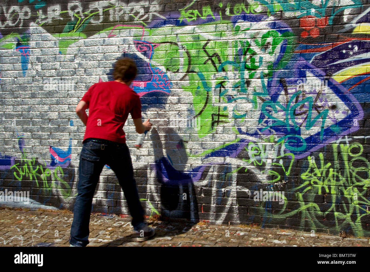 Young artist spray painting on a legalized graffiti wall in Dundee,UK
