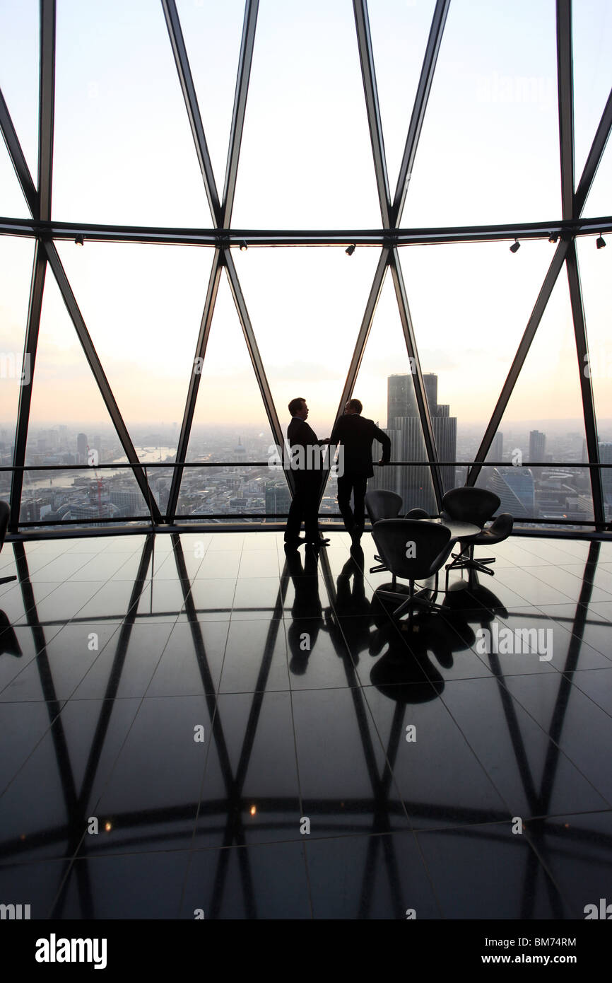 Businessmen stand and talk at the top of the Gherkin skyscraper in the city of London, U.K. Stock Photo