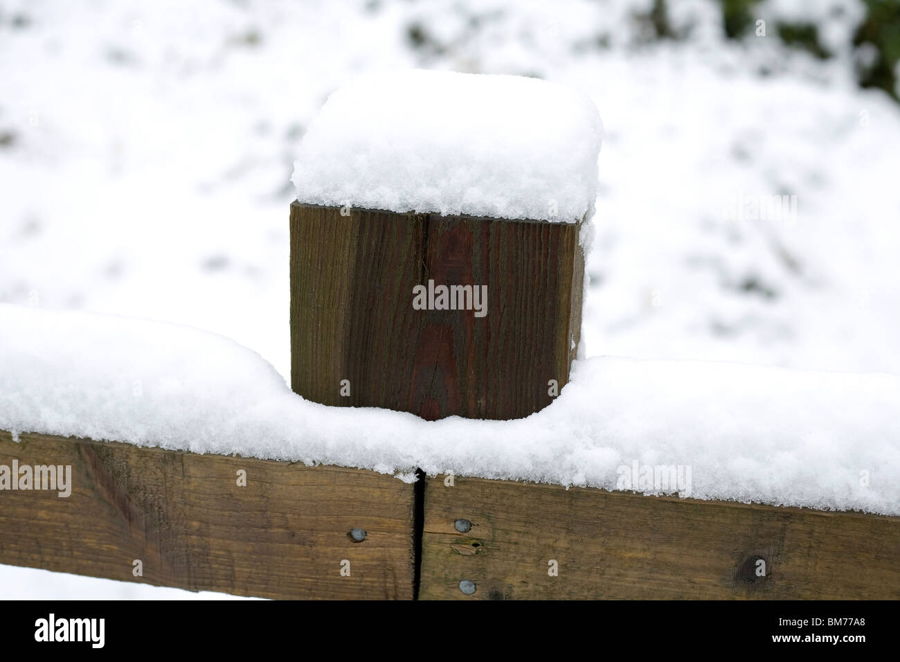 Wooden fence and fencepost topped by snow next to a footpath leading onto the sand dunes at Newton, Porthcawl Stock Photo