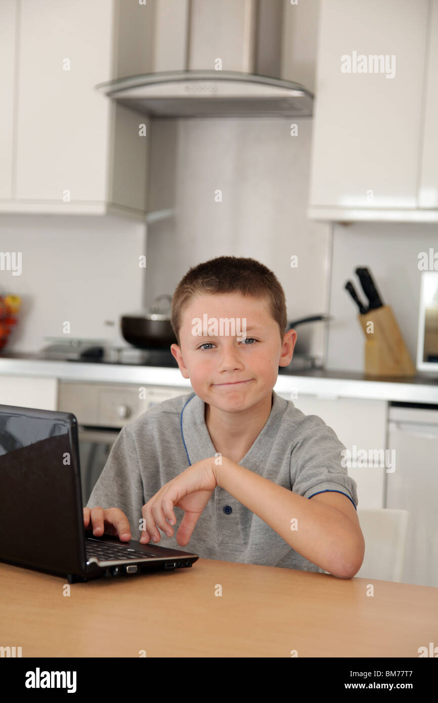 Young boy using notebook computer in the kitchen Stock Photo