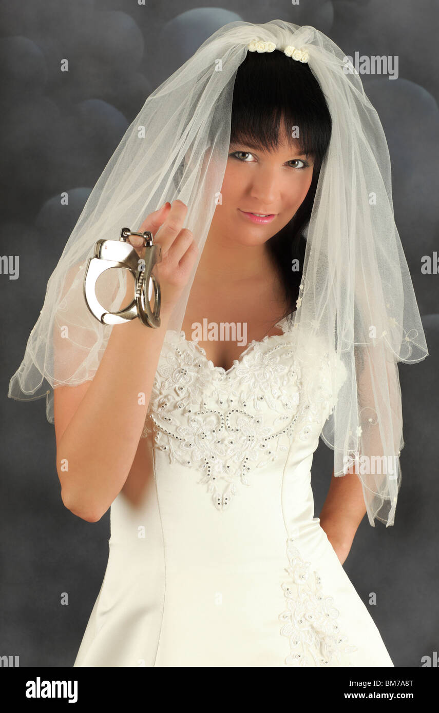 Portrait of an young bride offering marriage with handcuffs, studio