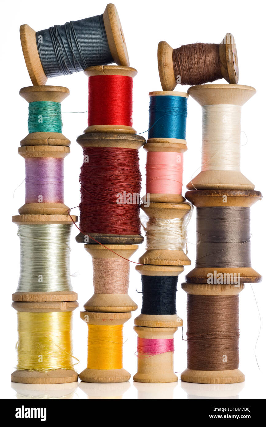 a collection of colorful wooden spools of thread on white Stock Photo