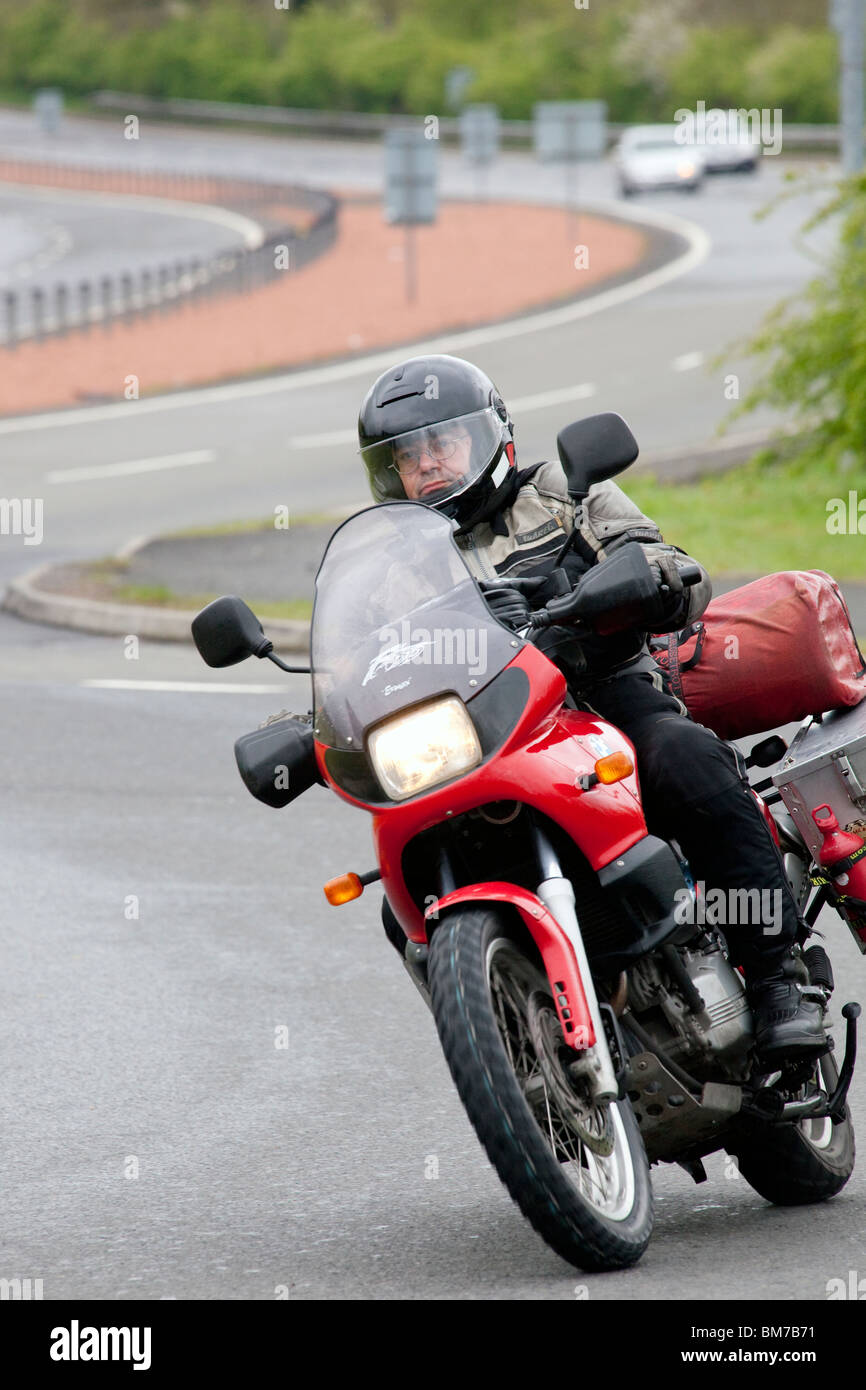 Motorcyclist on motorbike on roundabout on A75 dual carriageway near Dumfries heading for the North West 200 in Ireland Stock Photo